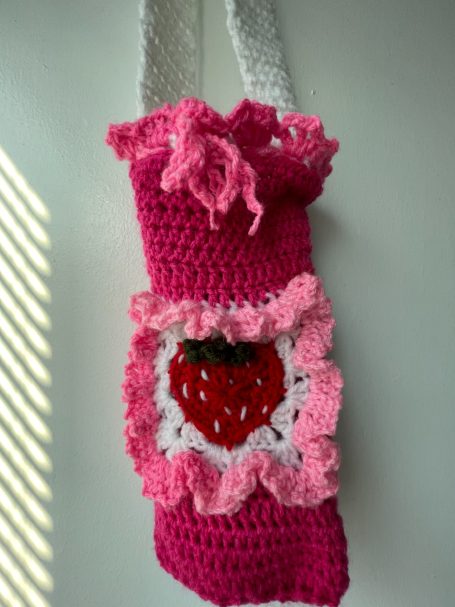 Pink crocheted water bottle holder with strawberry in the middle